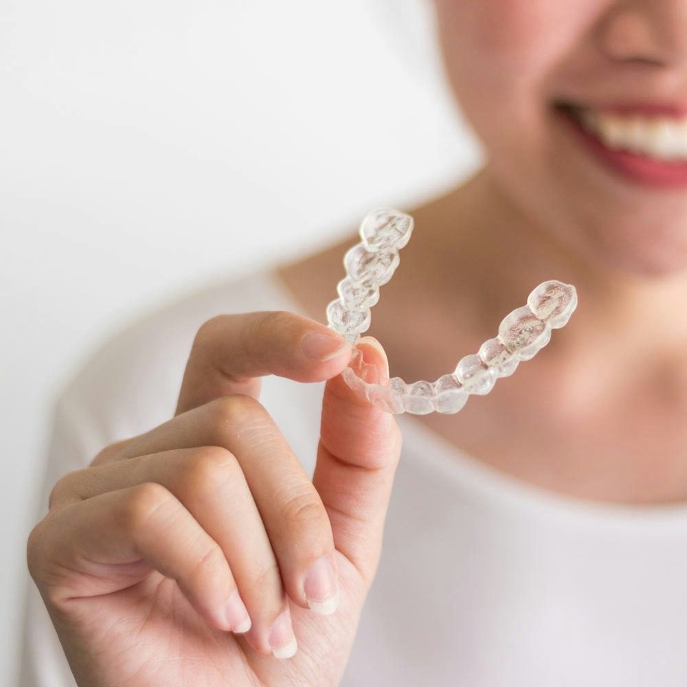Clear dental aligner held by person