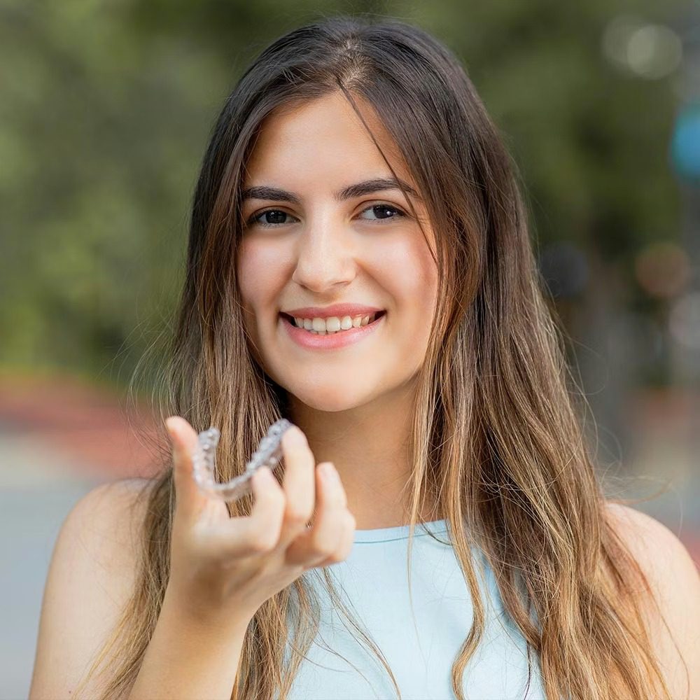 Woman displaying dental aligners outdoors