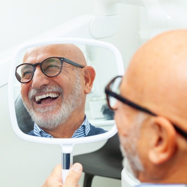 Man laughing while holding a mirror