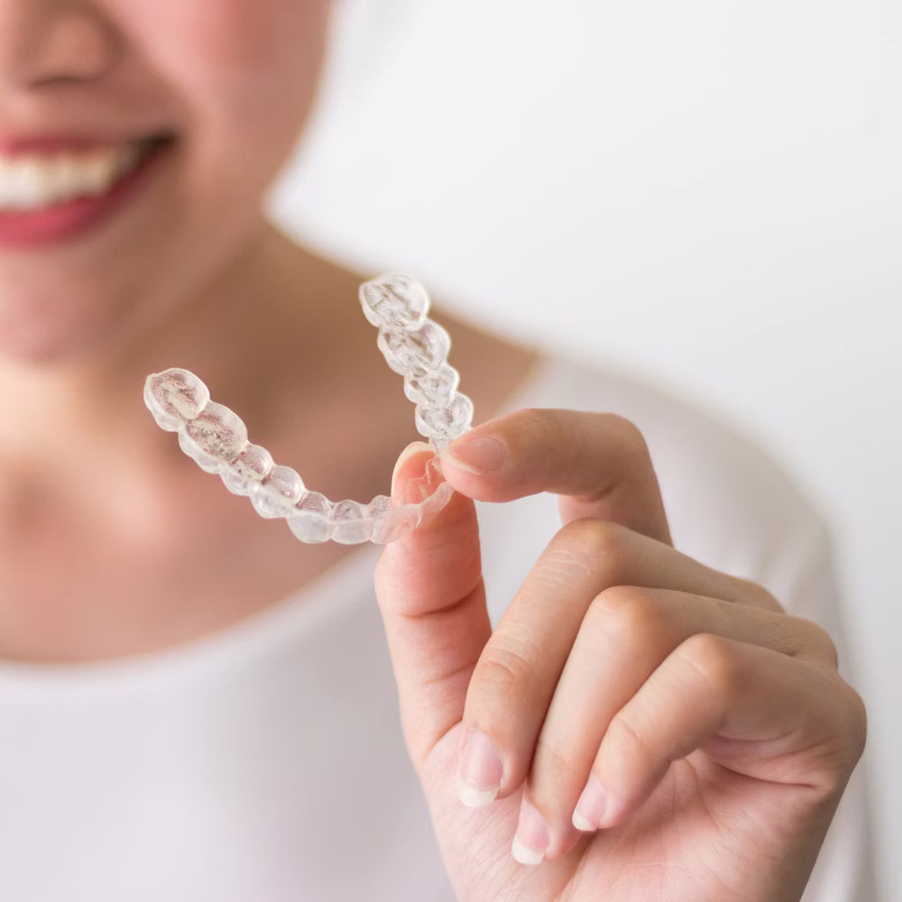 Woman holding clear dental aligner